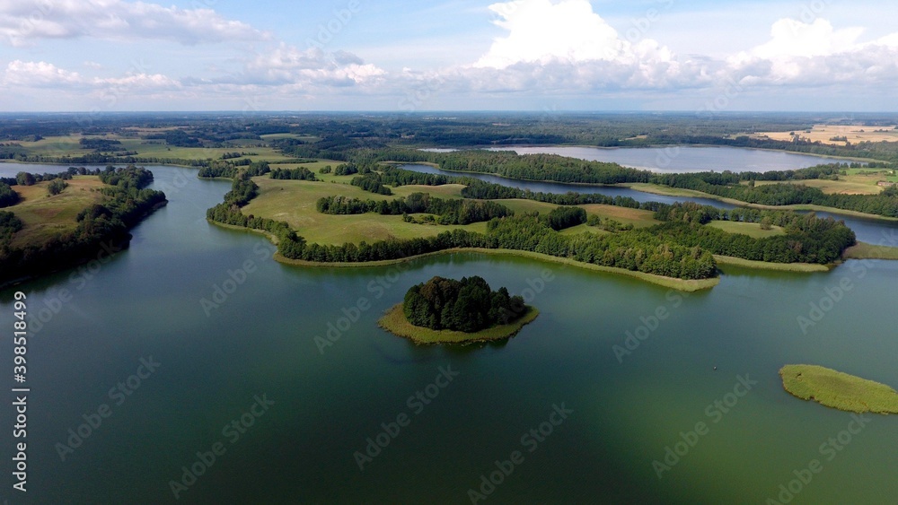 Aerial view of of small islands on a blue lake Saimaa. Landscape with drone. Blue lakes, islands and green forests from above on a cloudy summer morning.