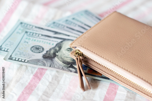 Stylish wallet and dollars lie on a striped cloth