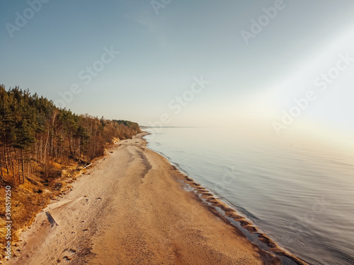 Sea shore at sunset with a sandy beach  sea with very small waves  the sun is very strong