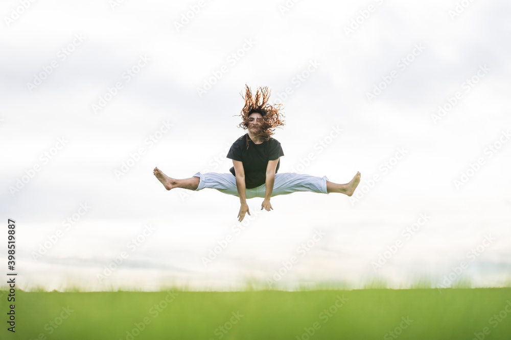 Carefree young athlete doing splits against sky Carefree young athlete doing splits against sky