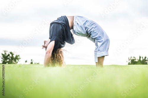 Female acrobat bending over backwards in park photo