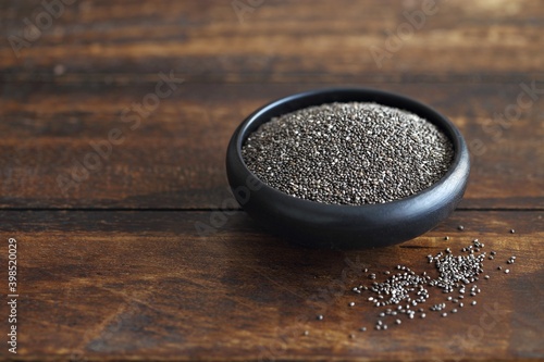 Chia seeds in a black ceramic bowl. Dark concrete background photo