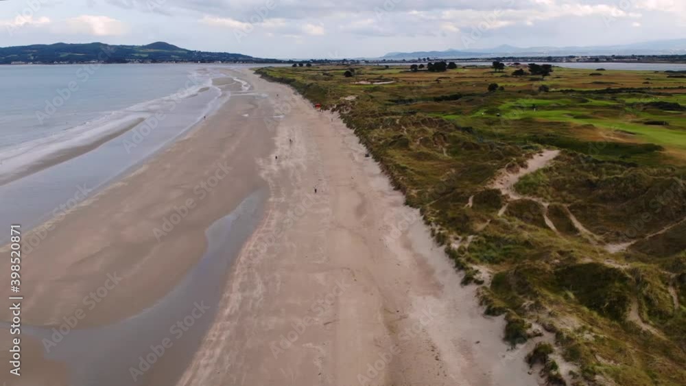 Drone fly over Portmarnock Beach and golf club, Howth Heads on background. Cloudy day in Ireland Drone fly over Portmarnock Beach and golf club, Howth Heads on background. Cloudy day in Ireland