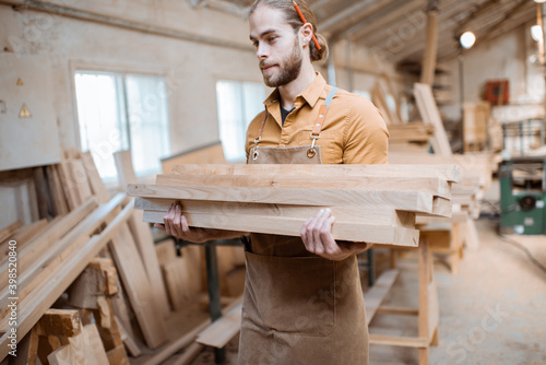 Carpenter carrying pine planks in the warehosue photo