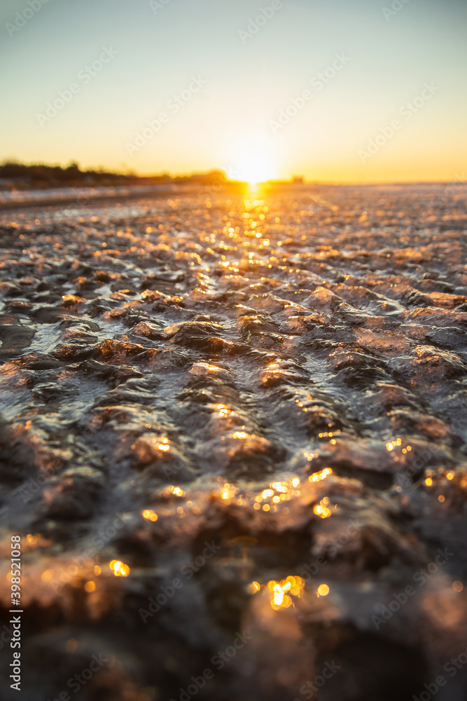 Obraz premium Frozen sea beach on the sinset. Ice covered sand waves.