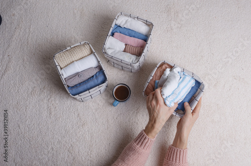 A woman folds clothes and puts them in baskets and boxes. Minimalism in the Scandinavian style. photo