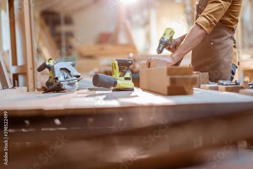 Fotografi Carpenter working with modern cordless tools and wooden bars on the workbench at