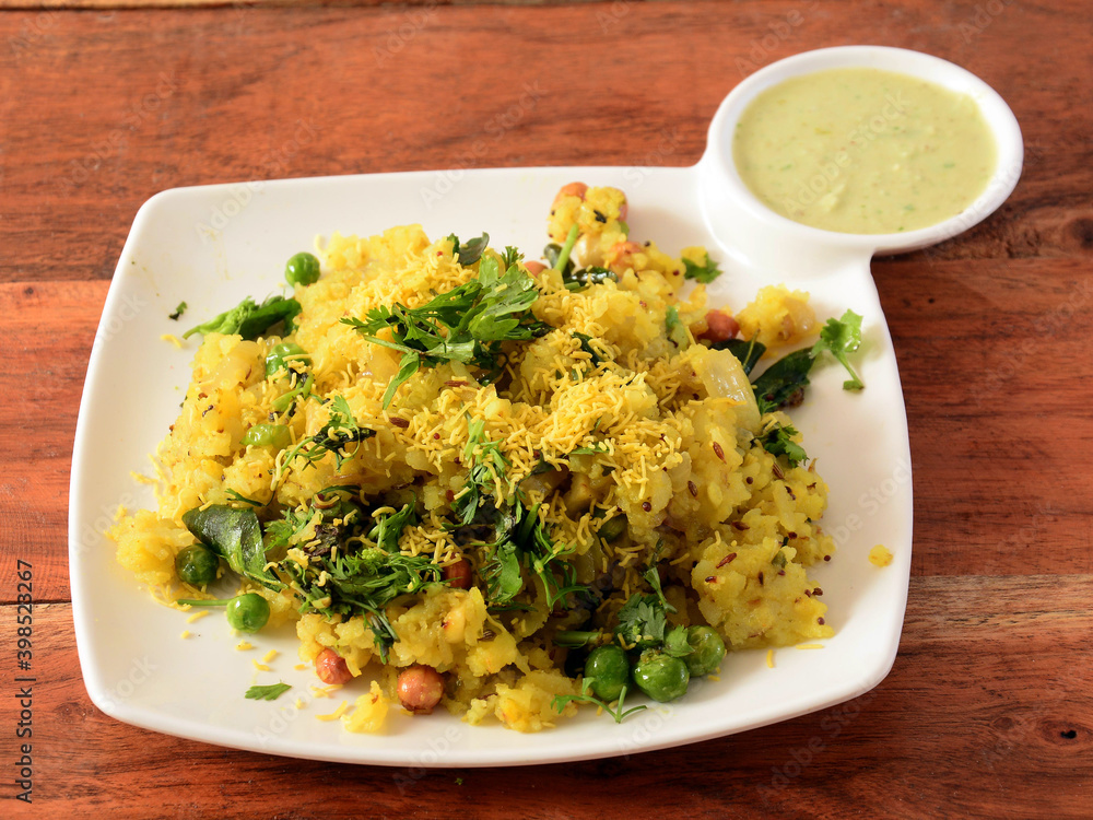 Poha, made with flattened rice, typically Western Indian breakfast, served in a plate over a rustic wooden background, selective focus