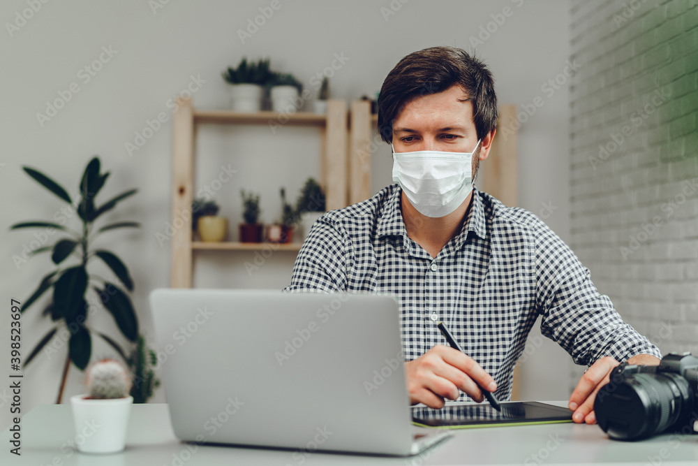 Man working on laptop at home and wearing medical mask Man working on laptop at home and wearing medical mask
