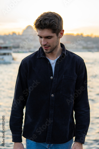 Young stylish man standing in Istanbul near Bosphorus on the sunset with a Mosque 