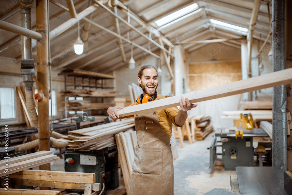 Handsome carpenter choosing planks for his woodwork at the joiners warehouse