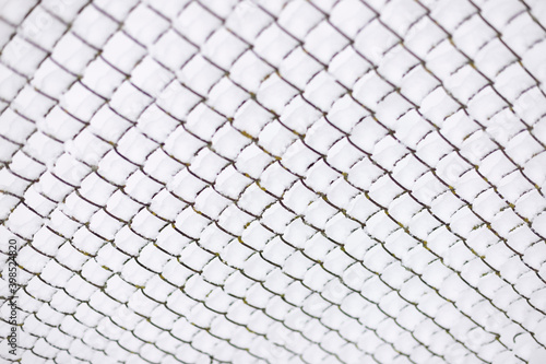 Snow piled on the wires of a chain link fence