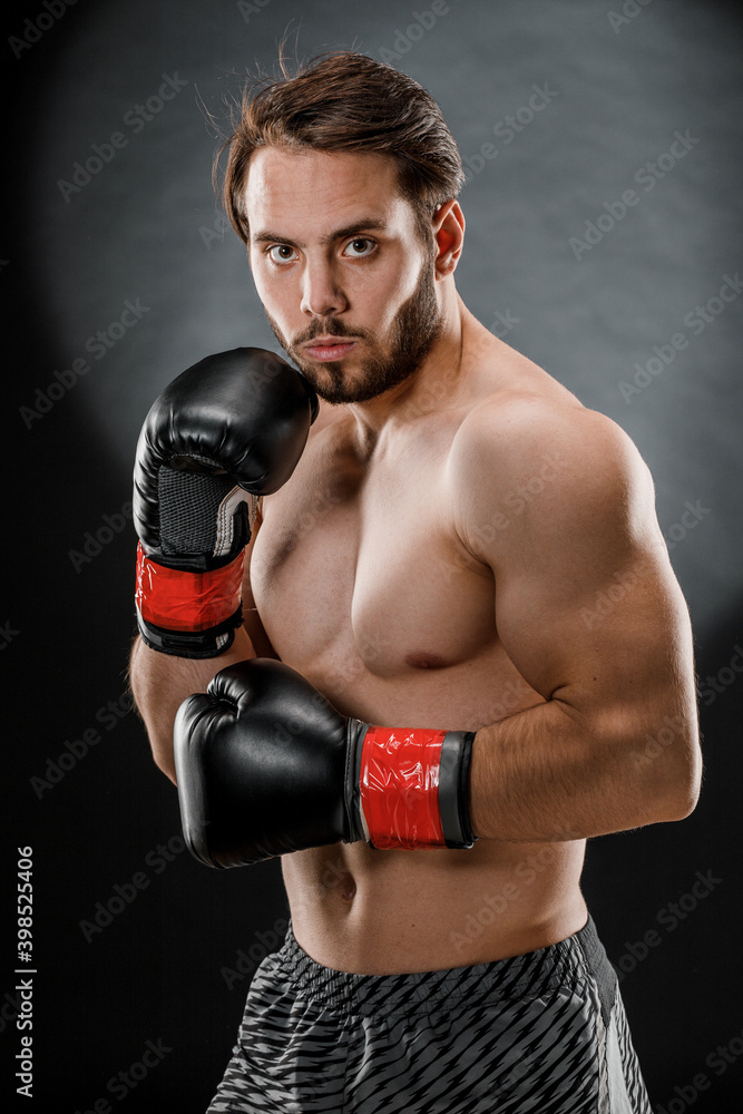 A man in Boxing gloves. A man Boxing on a black background. The concept of a healthy lifestyle