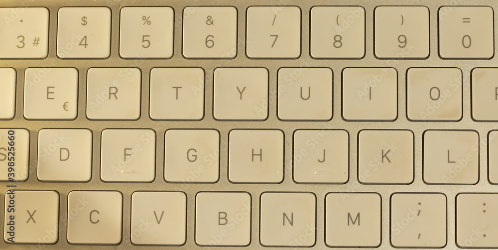 En la foto, aparece un teclado blanco elegante minimalista. En una mesa de madera limpia y elegante.  Este teclado se utiliza para trabajar desde casa con mucha seguridad.