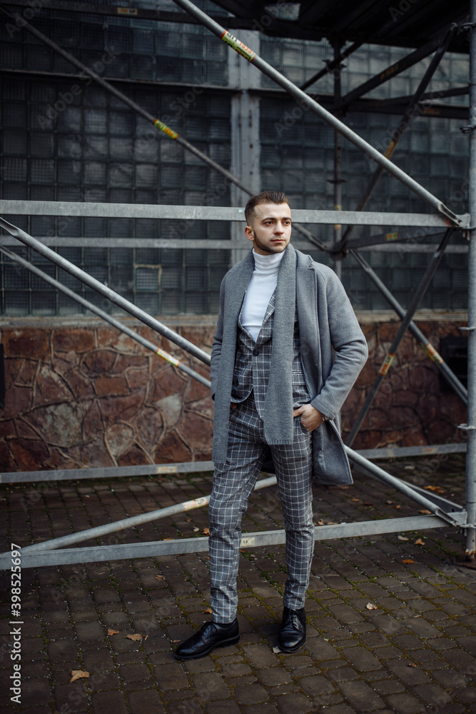 Full length body size photo ofcurious young man in stylish outfit wearing plaid suit grey coat scarf Full length body size photo ofcurious young man in stylish outfit wearing plaid suit grey coat scarf