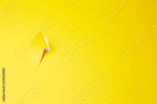 Right-up arrow cutted from solid sheet of yellow paper and curved up of one side with white paper underlay showing growth of stock market or up direction