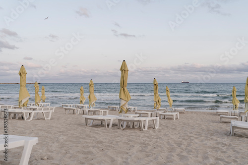 Beach umbrellas and deck chairs on empty beach at dusk photo