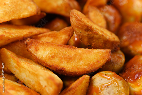 Fried potatoes with sausages close up.