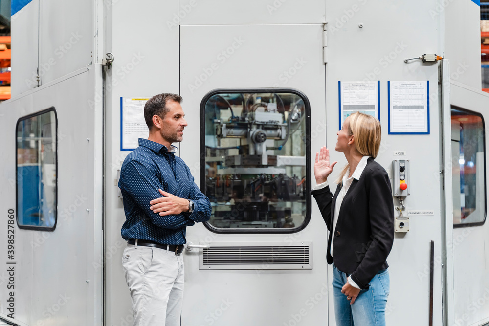 Businesswoman explaining male colleague while standing by control room in industry Businesswoman explaining male colleague while standing by control room in industry