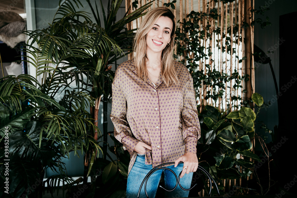 Smiling businesswoman standing against plants at creative office Smiling businesswoman standing against plants at creative office