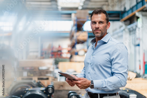 Confident businessman holding digital tablet while standing at factory photo