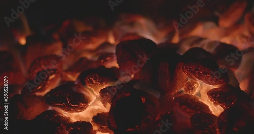 Glowing coals in a campfire. Flames glow from lump charcoal in a steel park grill for barbequing. 