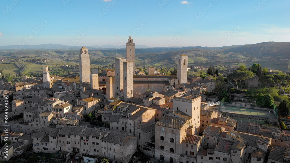 drone is flying over italian town San Gimignano in sunny day in summer, approaching to historical towers