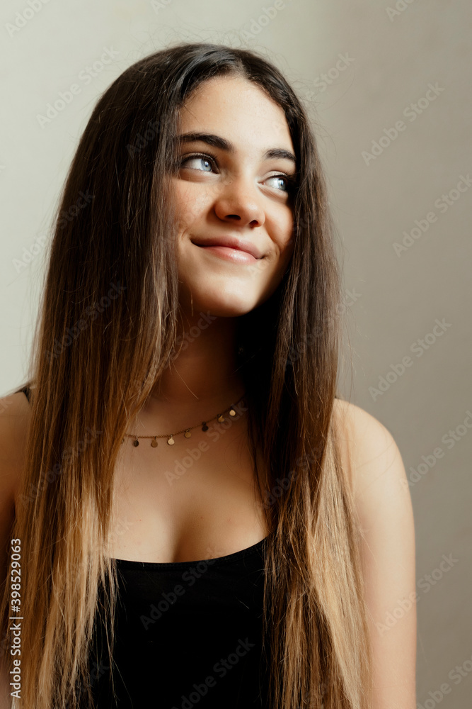 Smiling long hair girl sitting against white wall at home Smiling long hair girl sitting against white wall at home