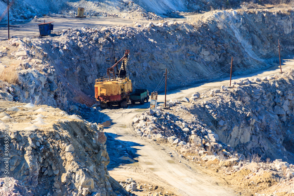 Big yellow excavator working in a granite quarry Big yellow excavator working in a granite quarry