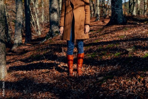 Woman wearing jacket and rubber boot standing on fallen leaf in forest photo