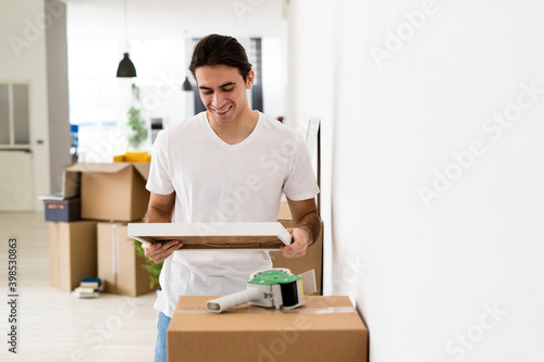 Smiling man looking at picture frame while reliving memories at new apartment