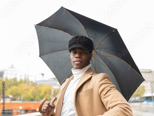 Young man holding umbrella while standing outdoors photo