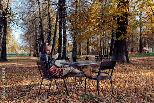 Mid adult woman looking up while sitting in public park photo