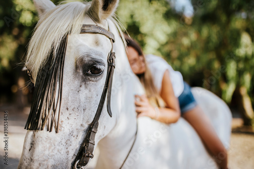 White horse looking a tcamera while carrying beautiful young woman photo