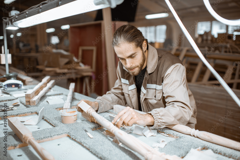 Manual worker finishing wooden products, spackling and grinding baluster at the carpentry manufacturing Manual worker finishing wooden products, spackling and grinding baluster at the carpentry manufacturing