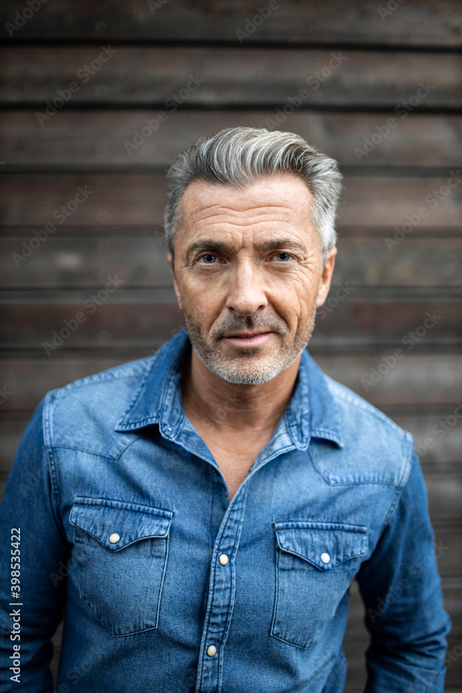 Confident man standing against wooden wall Confident man standing against wooden wall