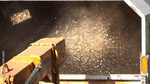 Close-up of wood chips expelled from the chute of wood chipper into the back of a truck in slow motion. photo
