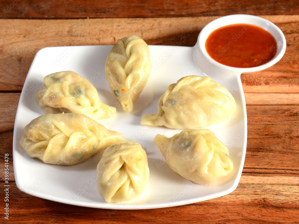 Veg steam momo. Nepalese Traditional dish Momo stuffed with vegetables and then cooked and served with sauce over a rustic wooden background, selective focus Veg steam momo. Nepalese Traditional dish Momo stuffed with vegetables and then cooked and served with sauce over a rustic wooden background, selective focus