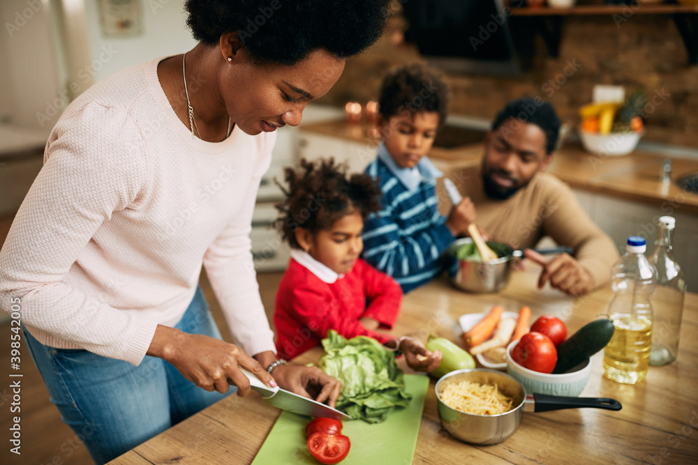 Happy black family preparing healthy meal in the kitchen.