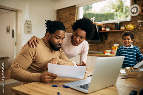 African American parents analyzing paperwork together at home.