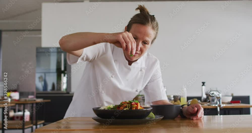 Caucasian female chef preparing a dish and smiling in a kitchen Caucasian female chef preparing a dish and smiling in a kitchen