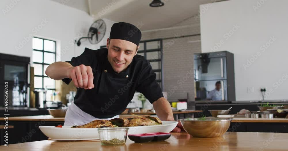 Caucasian male chef preparing a dish and smiling in a kitchen Caucasian male chef preparing a dish and smiling in a kitchen