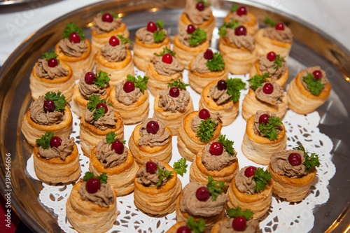 Tartlets of cod liver pate with green leaf grapes placed on a round plate. Cooking delicacies, healthy food snacks.