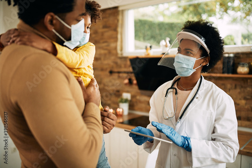African American family doctor communicating with father and daughter  during home visit. photo