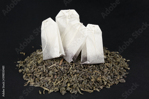 Choosing between leafy green tea and pocketed tea. A packet on a heap of dry large leaf tea.
