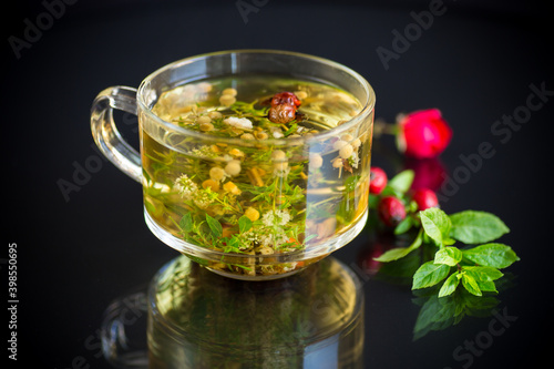hot herbal tea from various herbs in glass cup on black background