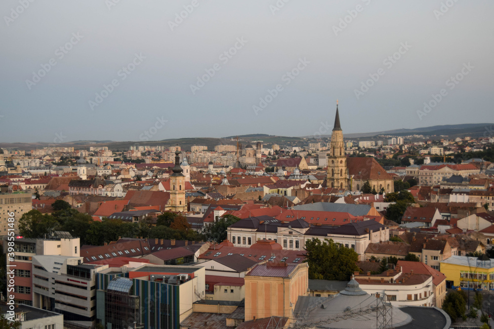 Cluj-Napoca,Romania- 07.20.2019: Aerial photography over the town center at the sunset. Sfantul Mihail Church,located in the center of the city,in Matei Corvin Square (Mathias Rex).