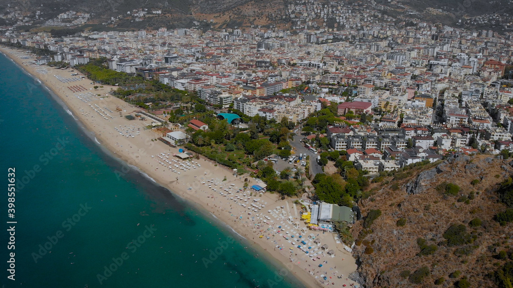 Turkish Alanya from above. In the frame, there are many houses on the shores of the Mediterranean Sea, the city is located in a picturesque place near the mountains.