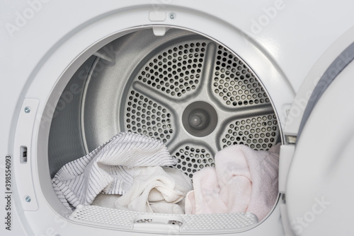 Interior view of the tumble dryer with dry linen. Conceptual image of housework and laundry.