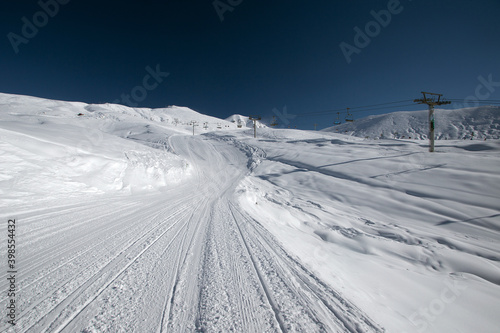 Recently prepared ski piste, ski lift and snowy mountains. Winter ski resort